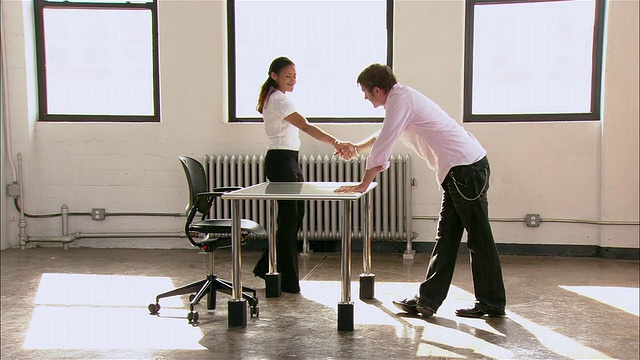 在纽约市，一家初创公司的合伙人在空荡荡的阁楼里接过新桌子和椅子，指着办公室的另一部分，然后走过去视频下载