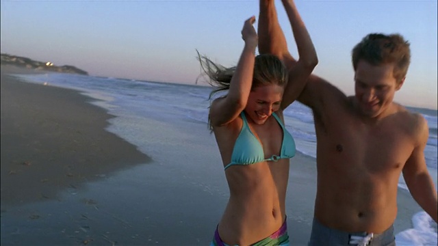 慢动作中镜头夫妇在海滩上跑步视频下载