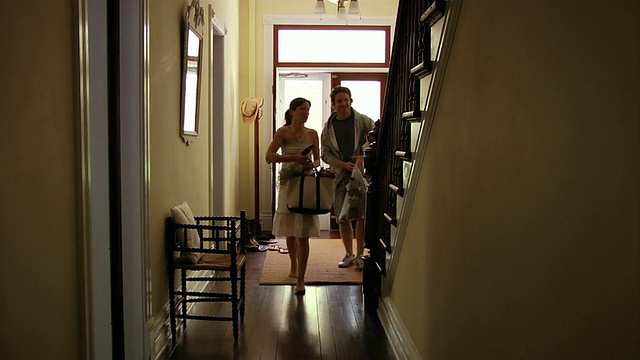 中镜头的男人和女人进入前门/女人向他们打招呼，然后上楼视频下载