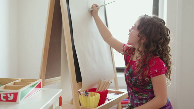 小姑娘(6-7岁)在画架上画画，在美国纽约布鲁克林的游戏室视频素材