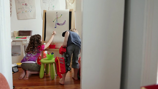 WS女孩(6-7岁)在游戏室的画架上画画，男孩(2-5岁)拿走玩具/纽约布鲁克林，美国视频素材