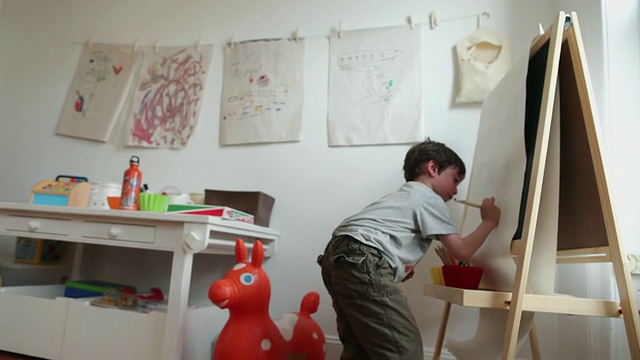男孩女士(4-5)在画架上画画，在游戏室/布鲁克林，纽约，美国视频下载