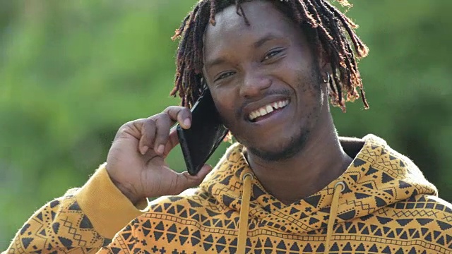 年轻快乐英俊的非洲男子在户外街道上打电话时微笑视频素材