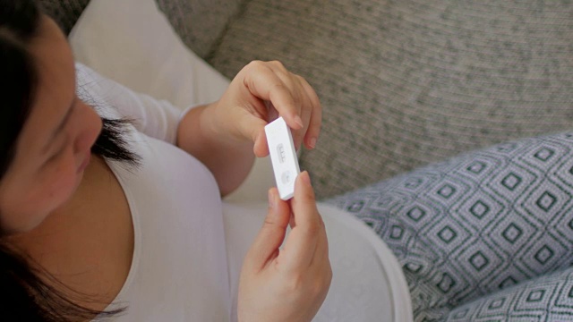 孕妇拿着验孕棒在客厅视频素材