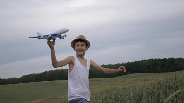 梦想家的乡村男孩手里拿着一架飞机跑过田野视频素材