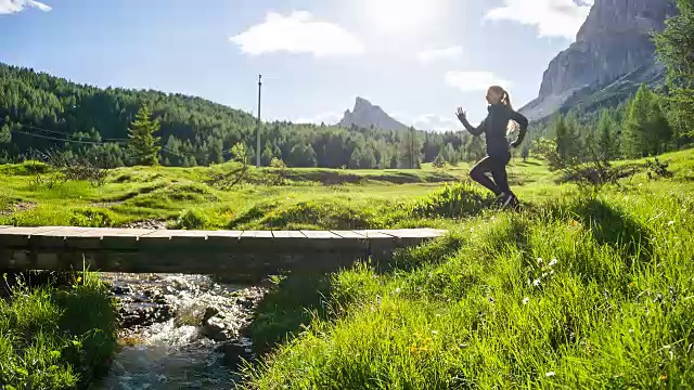 健康的女人在户外慢跑在小溪上的一座桥视频素材