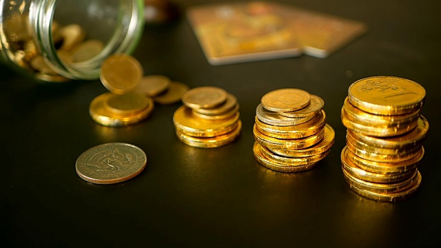 象征着投资、保值的理念。特写静物生活与增加专栏的金币在黑色的桌子上视频素材