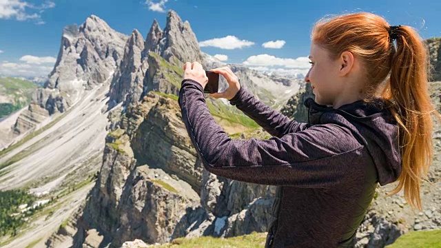 一名女性徒步旅行者在山顶用智能手机拍照视频下载