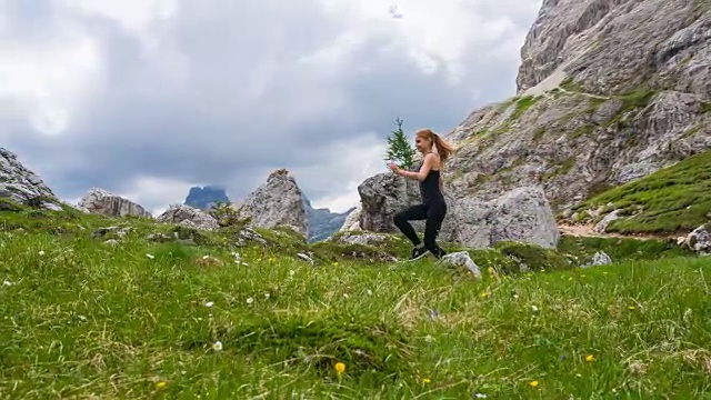 快乐的女运动员在山腰的绿色草地上奔跑视频素材