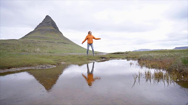 冰岛Kirkjufell山，女孩在大自然中嬉戏，跳跃和举起手臂的慢动作视频视频素材