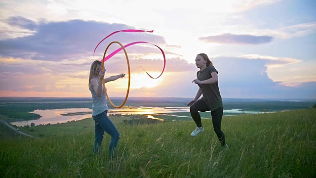 两个年轻女子在山上锻炼，夕阳西下时，女孩在山上跳圈视频素材