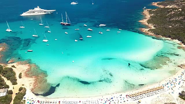 鸟瞰图翡翠和透明的地中海与白色的海滩和一些游艇。意大利撒丁岛翡翠海岸的大佩维罗湾。视频素材