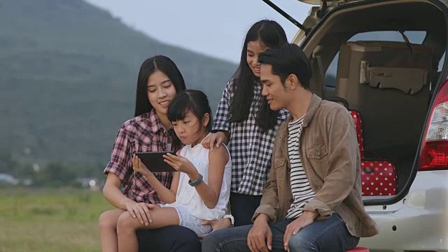 快乐的小女孩和亚洲家庭坐在车里玩尤克里里，享受公路旅行和暑假视频素材