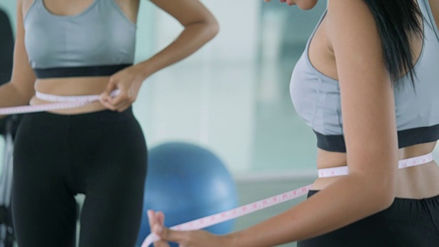 快乐的亚洲女人用测量尺在她的腰看着镜子。饮食概念视频素材