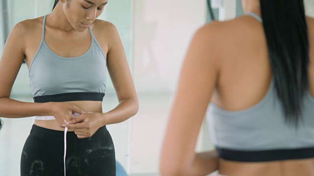 健身房里的女人在镜子前为自己的体重挣扎视频下载