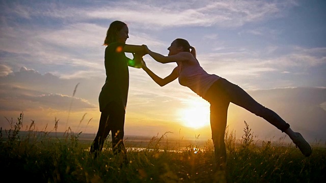 两名年轻的体操运动员在夏季日落时在草地上锻炼视频素材