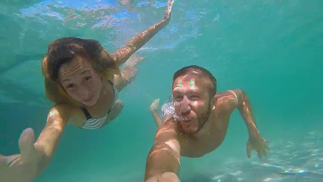 一对年轻夫妇用动作相机在水下自拍视频素材