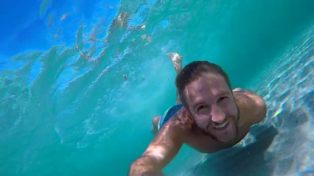 一名年轻人在水下游泳时用动作相机自拍视频素材