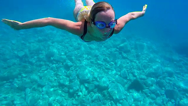 水下拍摄的年轻女子游泳在清澈的蓝色水享受度假在意大利撒丁岛视频素材