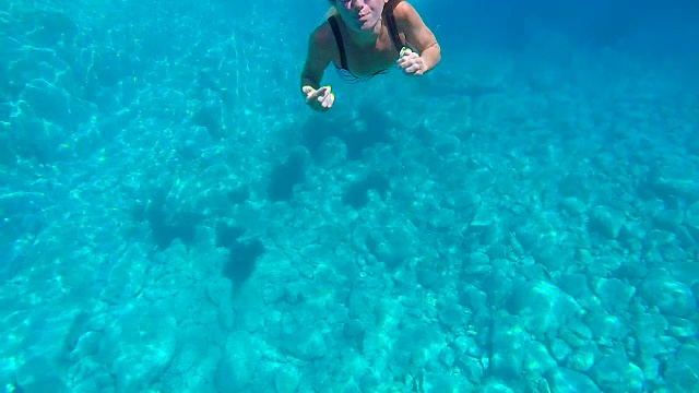 水下拍摄的年轻女子游泳在清澈的蓝色水享受度假在意大利撒丁岛视频素材