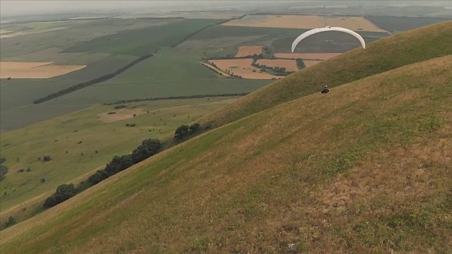 一个运动员骑着他的滑翔伞在燕子旁边飞行。无人机后续拍摄视频下载