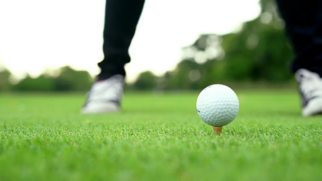 高尔夫球手走在绿色草地上，驾驶高尔夫球，高尔夫球棒和球。视频素材