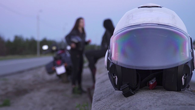 摩托车头盔在前景，女孩骑自行车后放松在背景视频下载
