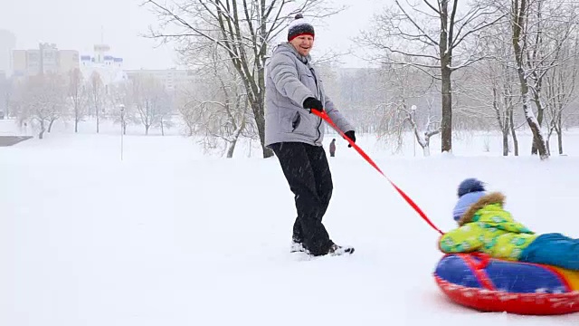 快乐的家庭和孩子们和狗在冬天在白雪覆盖的公园里玩耍视频素材
