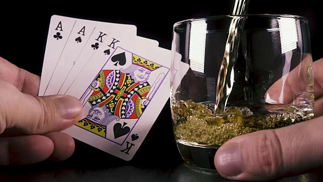慢动作强烈的酒精饮料倒入一个玻璃杯和扑克牌视频下载