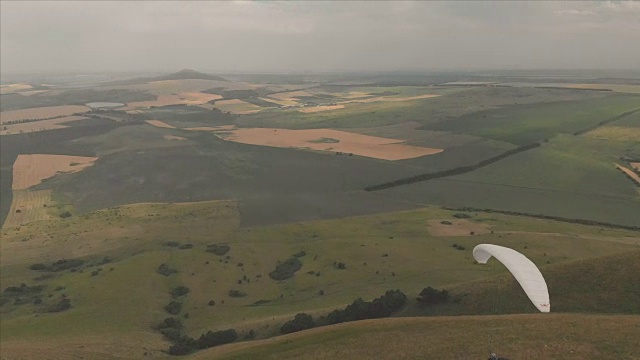 一个运动员骑着他的滑翔伞在燕子旁边飞行。无人机后续拍摄视频素材