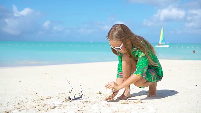 热带海滩上，一个手里拿着贝壳的可爱小女孩视频素材