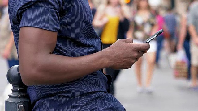 一名美国黑人在城市里用智能手机打字视频素材