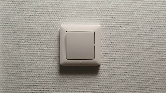 灯光关闭-男性用手关闭一个按钮，在浅灰色的墙上，正面视图视频下载