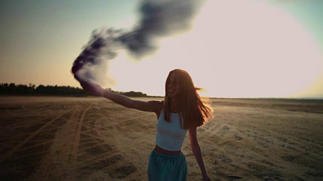 一个年轻女子在沙漠中拿着烟雾弹视频素材
