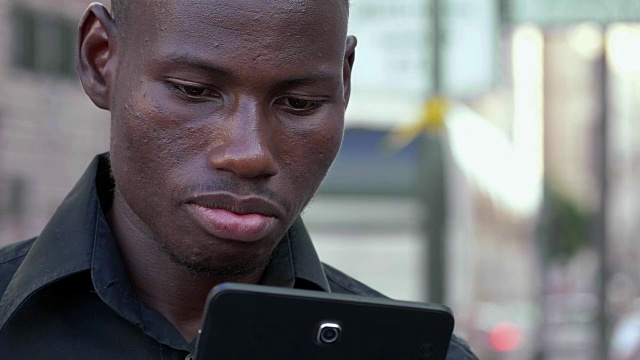专注于现代性、技术、青春。年轻的非洲黑人在智能手机上打字——户外视频素材