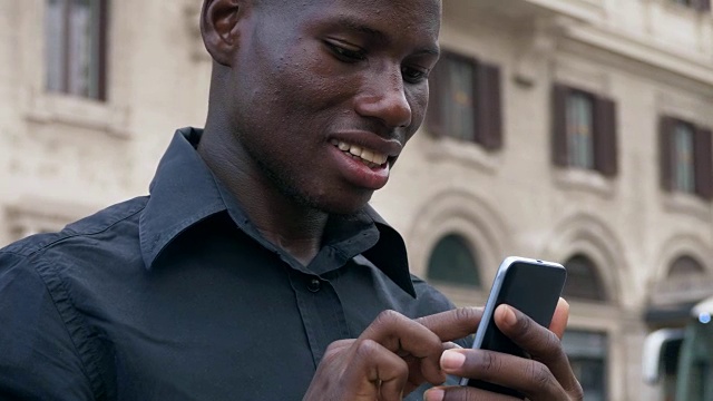 现代、科技、青春。年轻的非洲黑人在智能手机上打字——户外视频素材