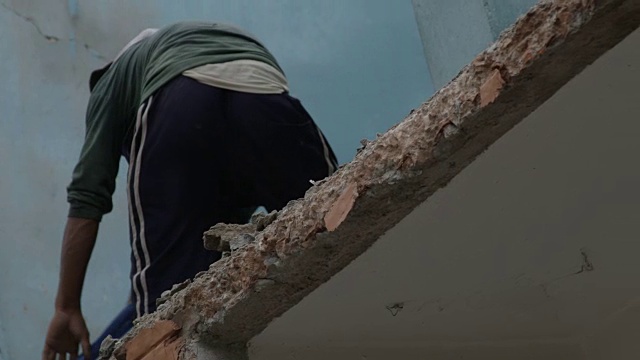 2015年7月31日，尼泊尔Barabise:一名男子从被摧毁的房屋中铲出碎石视频素材