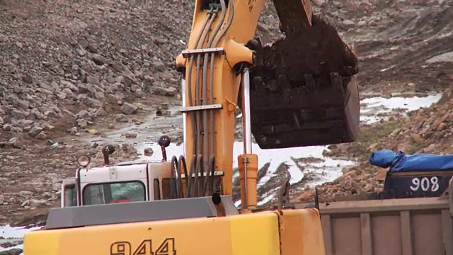 挖掘机在工地上挖土，然后把土倒进卡车视频素材