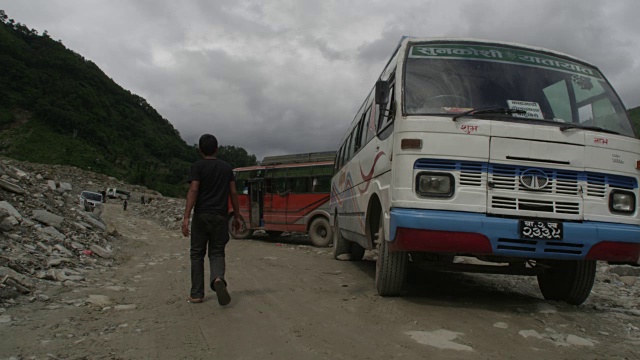 尼泊尔——2015年8月1日:公共汽车停在滑坡旁边，男孩慢慢走过视频下载
