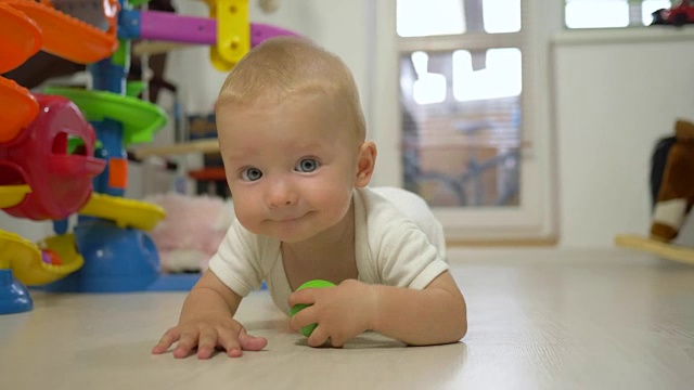 活跃的婴儿玩玩具和在地板上爬行特写视频下载
