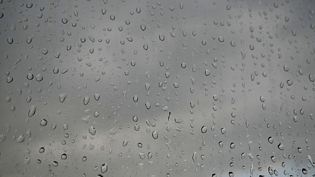 大量的雨水打在窗玻璃上。一股水流迅速地从玻璃杯里流下来。视频素材