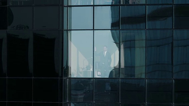 鸟瞰图镜头:从外面到办公大楼与商人工作和看窗外。美丽的飞行放大拍摄的金融商业区摩天大楼。视频素材