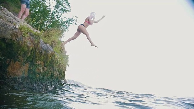 女孩从大自然的岩石中潜入水中，慢动作视频下载