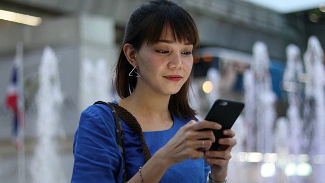 一名日本妇女在城市街道上使用手机视频素材