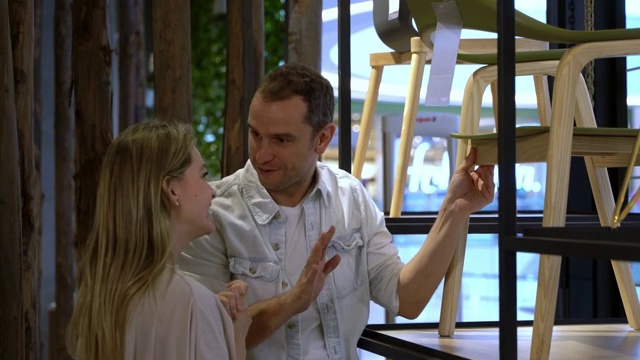 一对夫妇在一家设计家具店边聊天边欣赏一把椅子视频素材