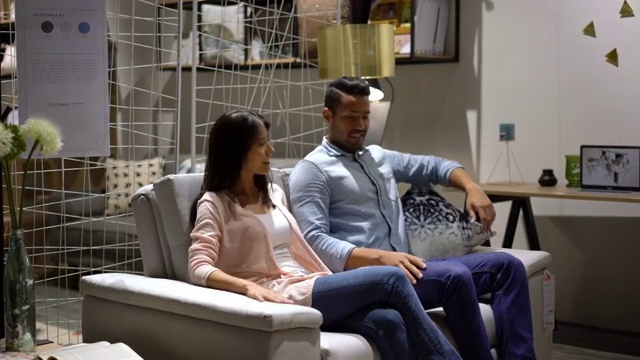 一对幸福的夫妇一边聊天一边在家具店试沙发视频下载
