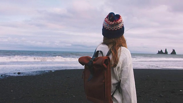 年轻迷人的女孩欣赏山的风景和海洋的海滩上，冰岛视频下载