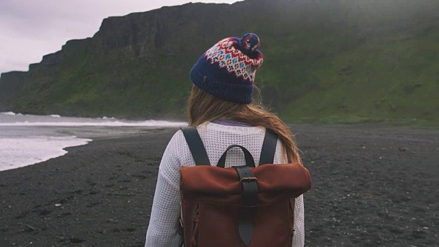 年轻迷人的女孩欣赏山的风景和海洋的海滩上，冰岛视频素材