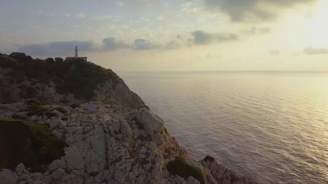日出时马略卡岛石崖上灯塔的航拍图视频素材