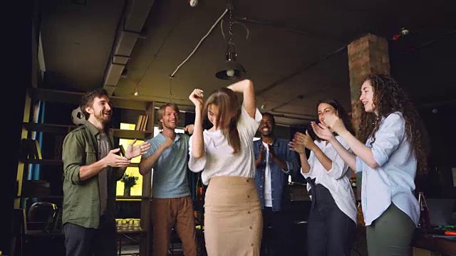 公司员工在公司聚会上跳舞，在现代阁楼风格的办公室，有魅力的年轻男女玩得开心，鼓掌和大笑。视频素材